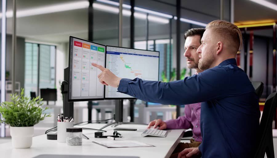 two people sit at a computer, one is pointing at the screen and explaining something to the other