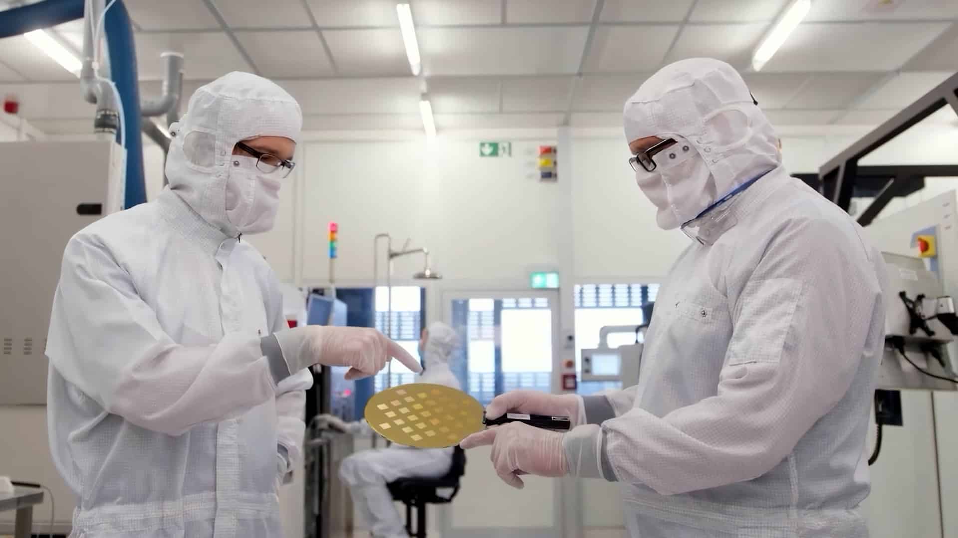 Close-up of two scientists working and holding a silicon wafer in a semiconductor factory.